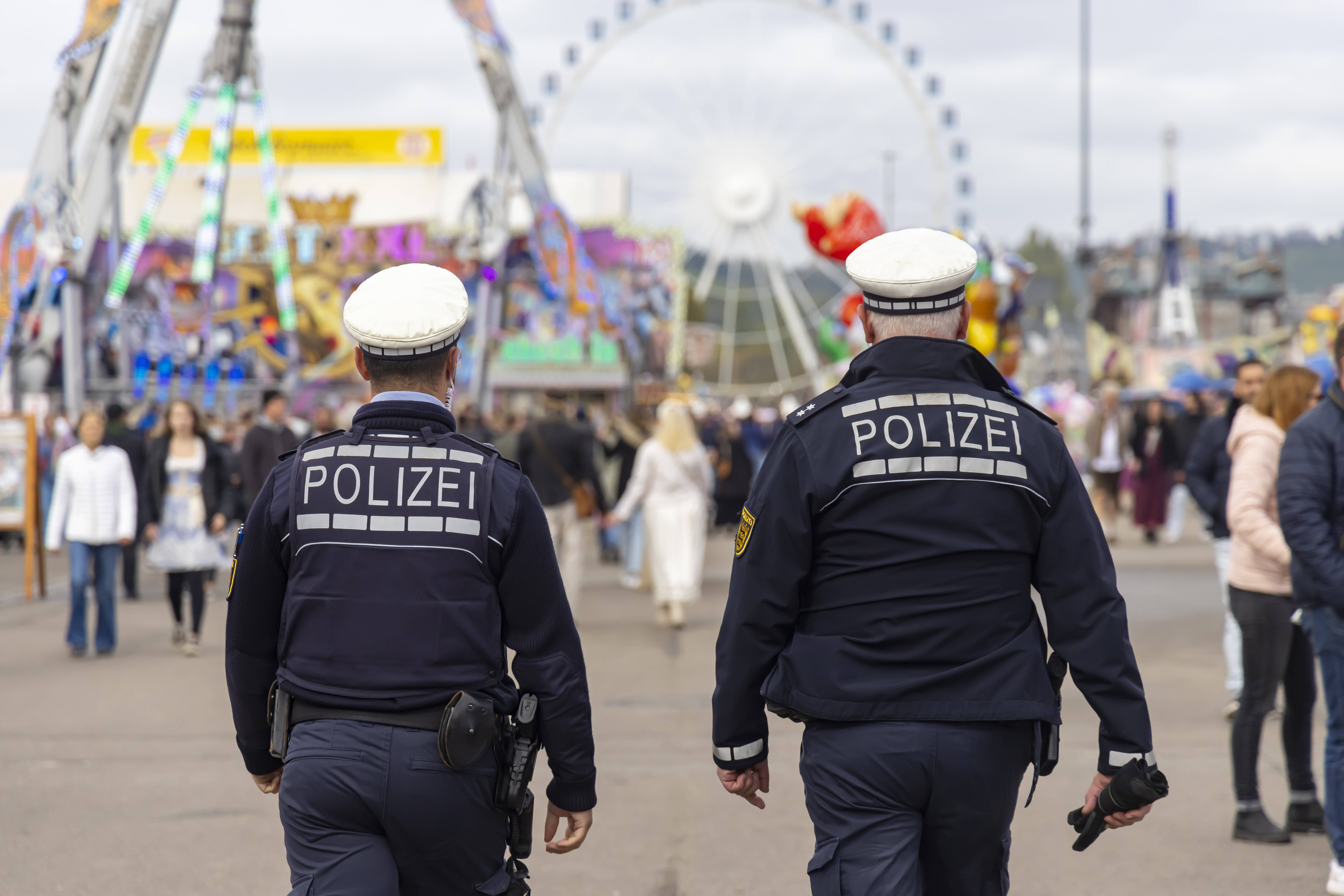 Zwei Polizisten laufen über einen Rummelplatz