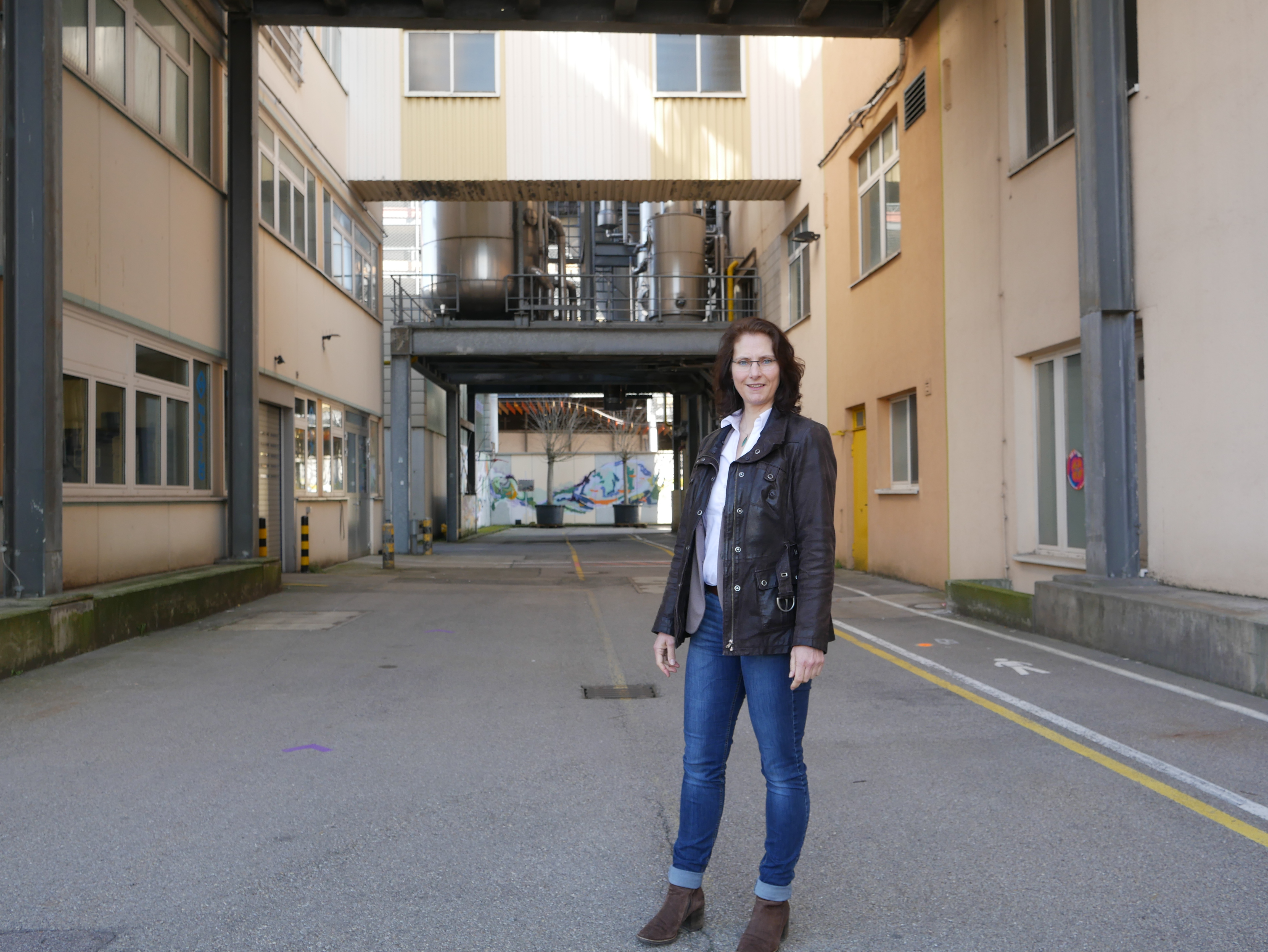 Frau steht auf einem Fabrikgelände