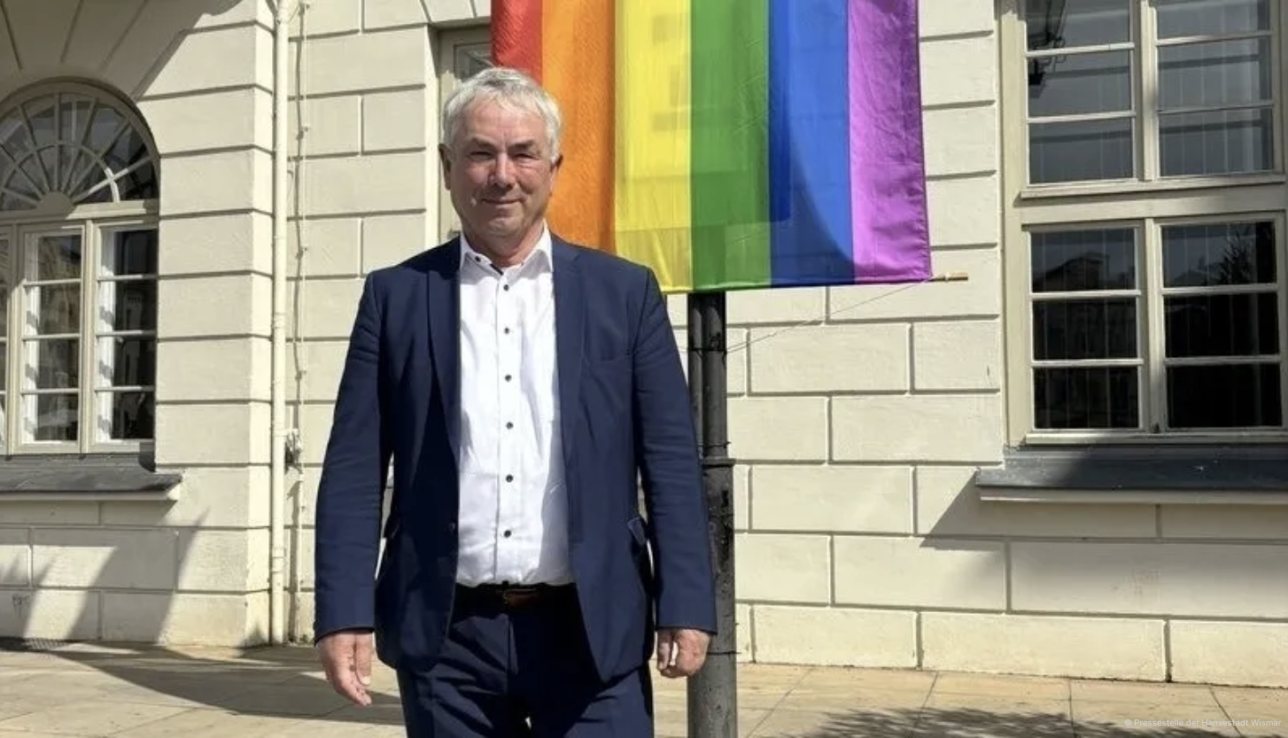 Thomas Beyer vor dem Rathaus mit Regenbogenflagge