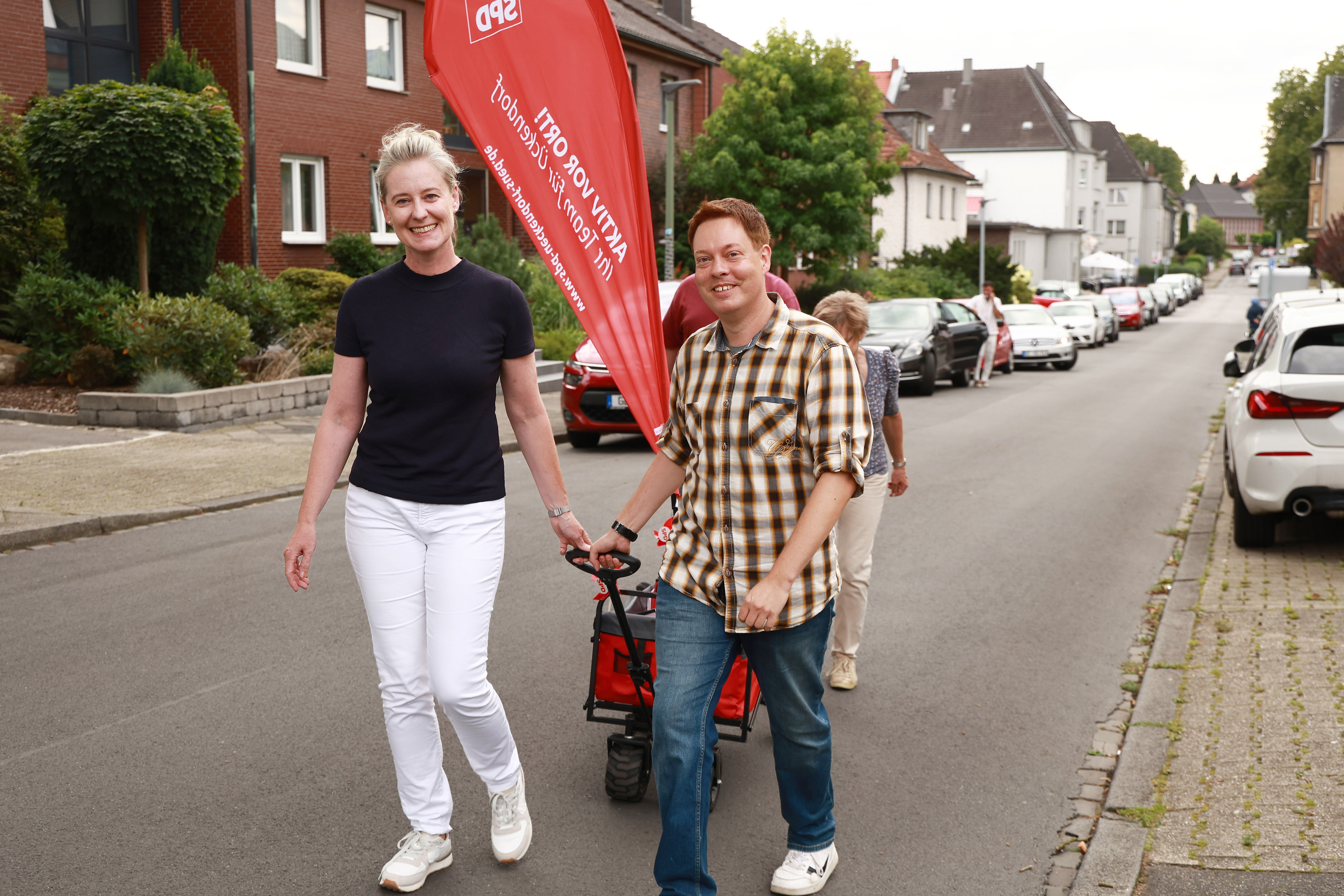 Andrea Henze und Uli Jacob ziehen eine Bollerwagen mit Wahlkampfmaterialien