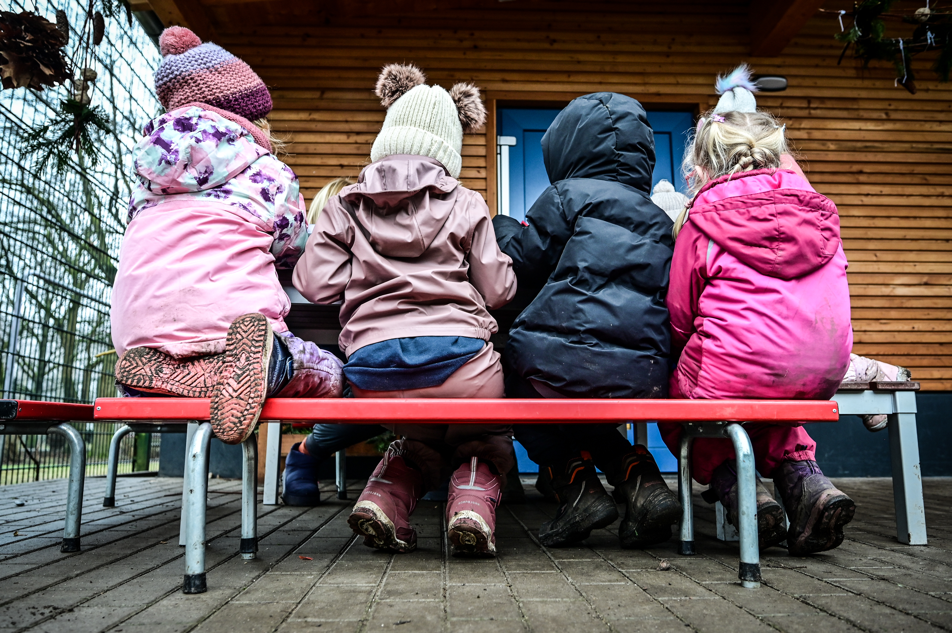 Kindergartenkinder sitzen auf einer Bank