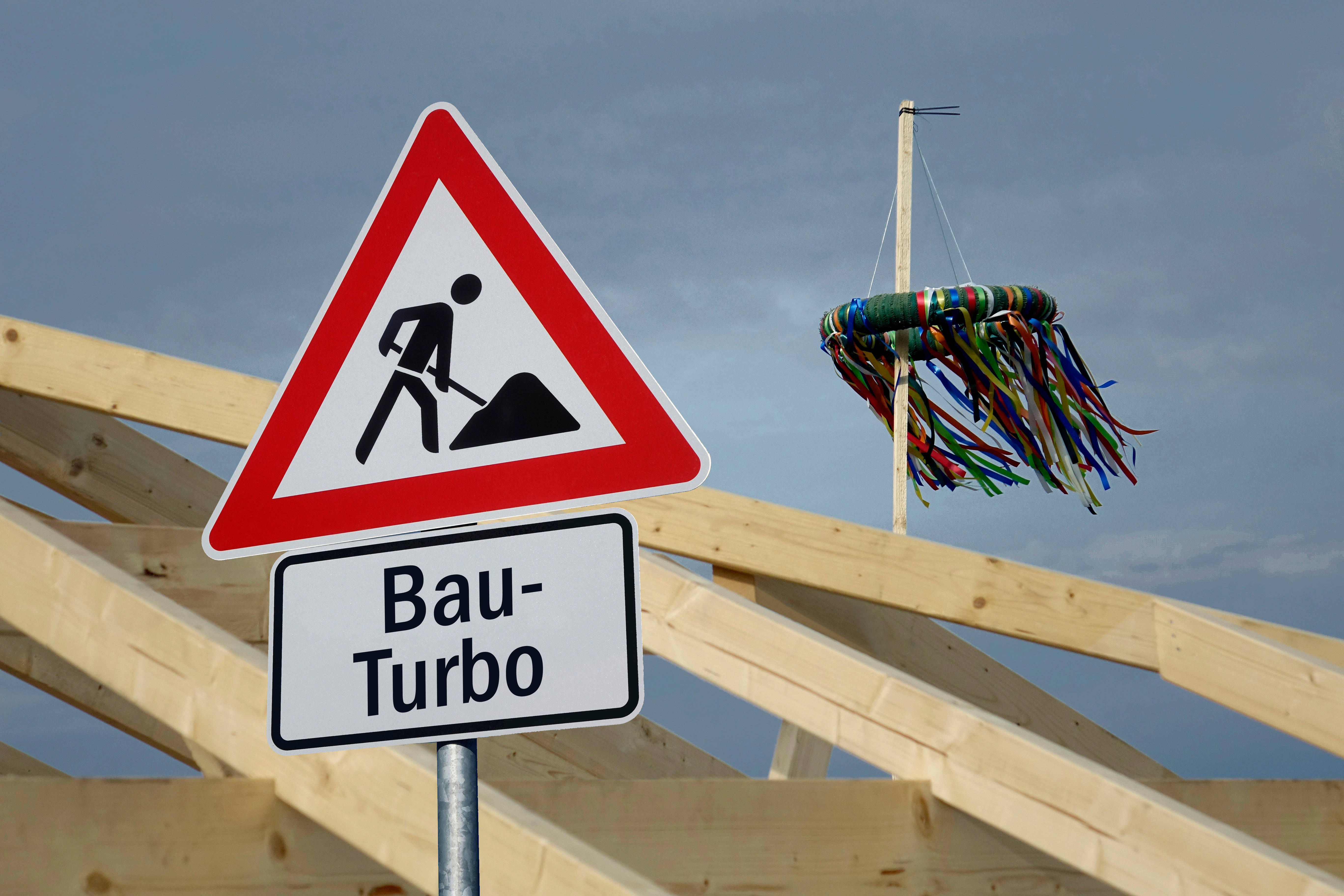 Baustellen-Schild mit Aufschrift Bau-Turbo vor ungedecktem Dach