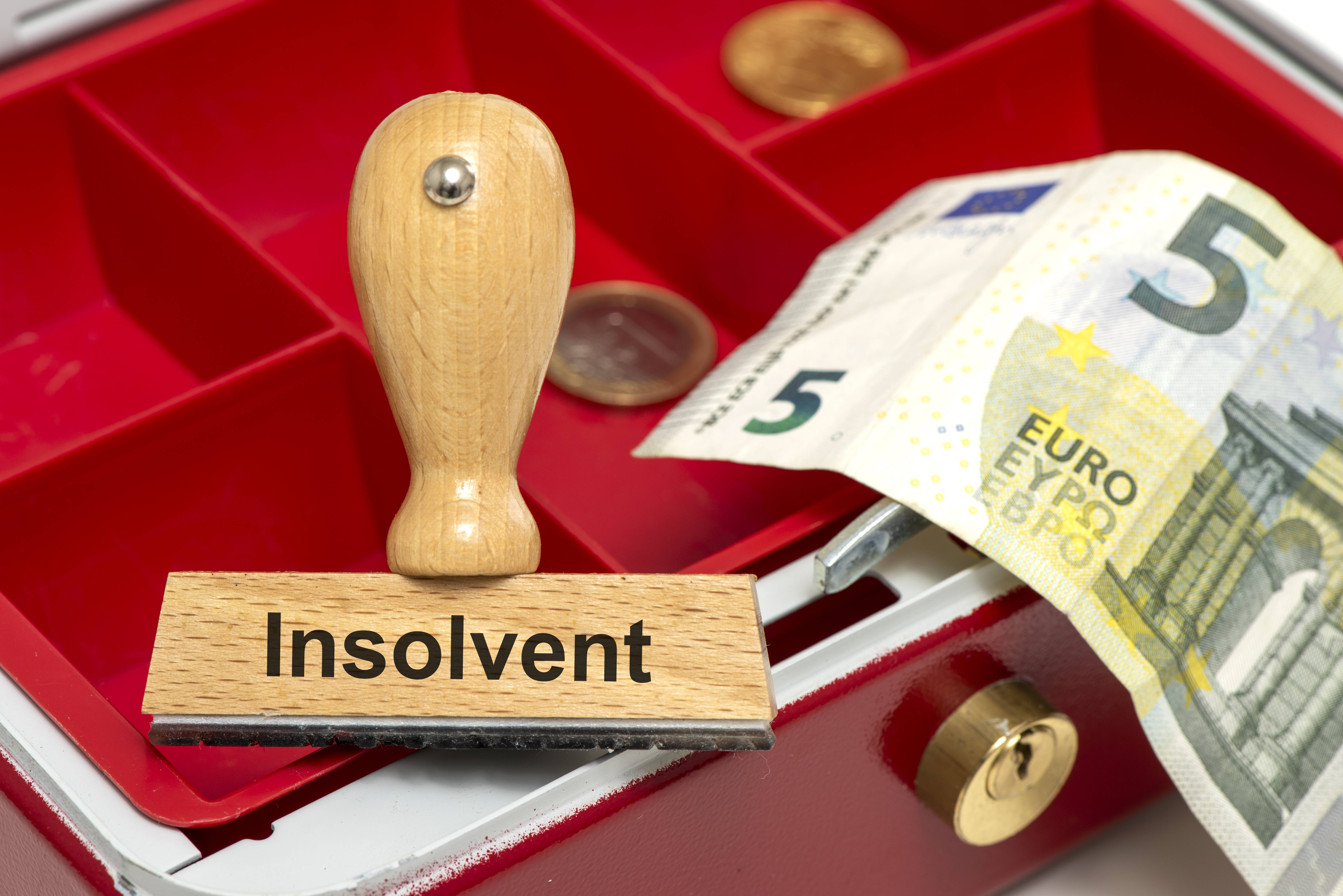 Stempel mit Aufdruck Insolvenz vor fast leerer Geldkassette